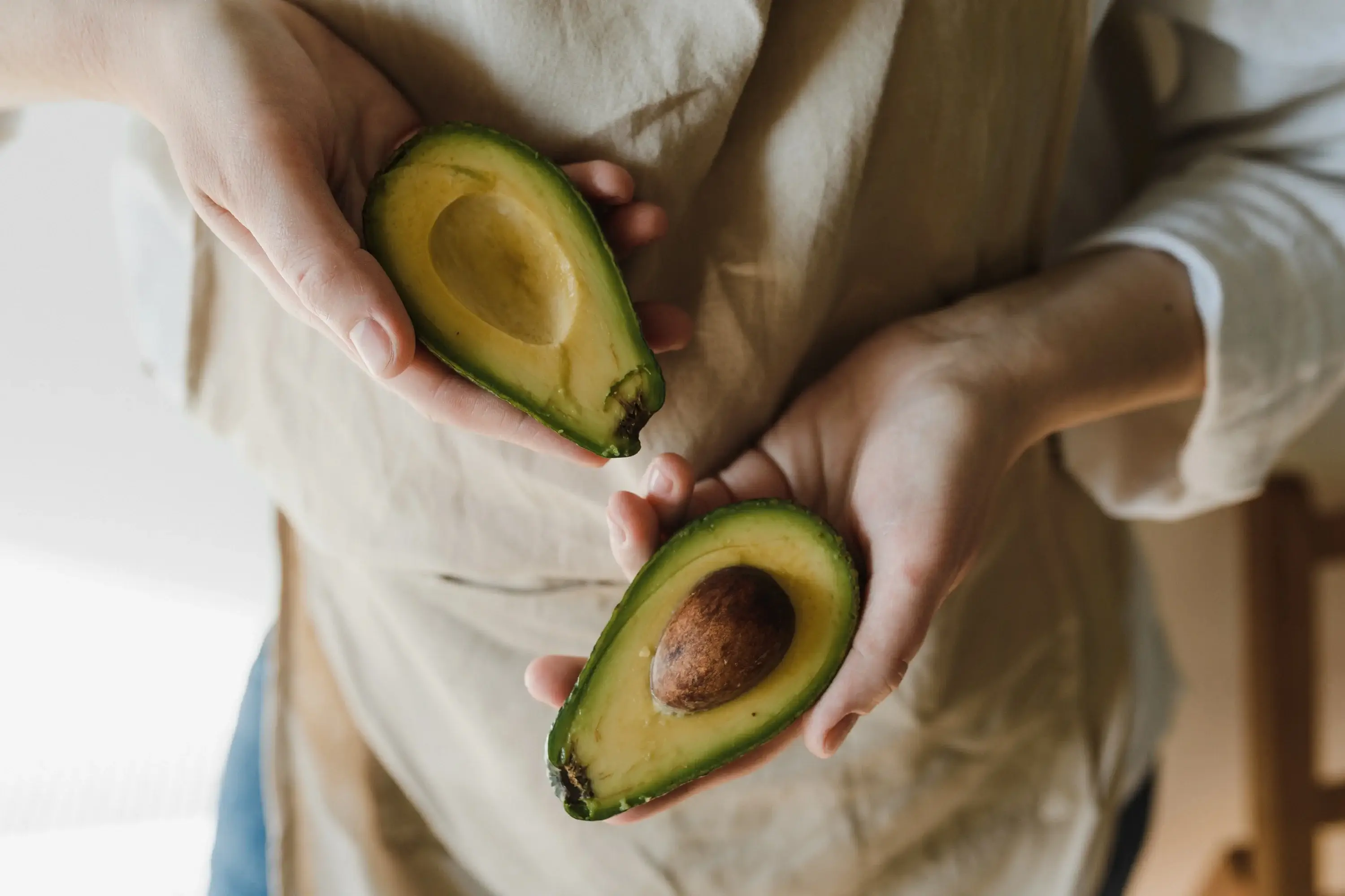 an open face avocado held in two hands